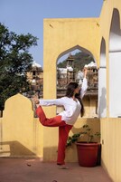 Una persona realizando una postura de yoga en un patio con un edificio al fondo.