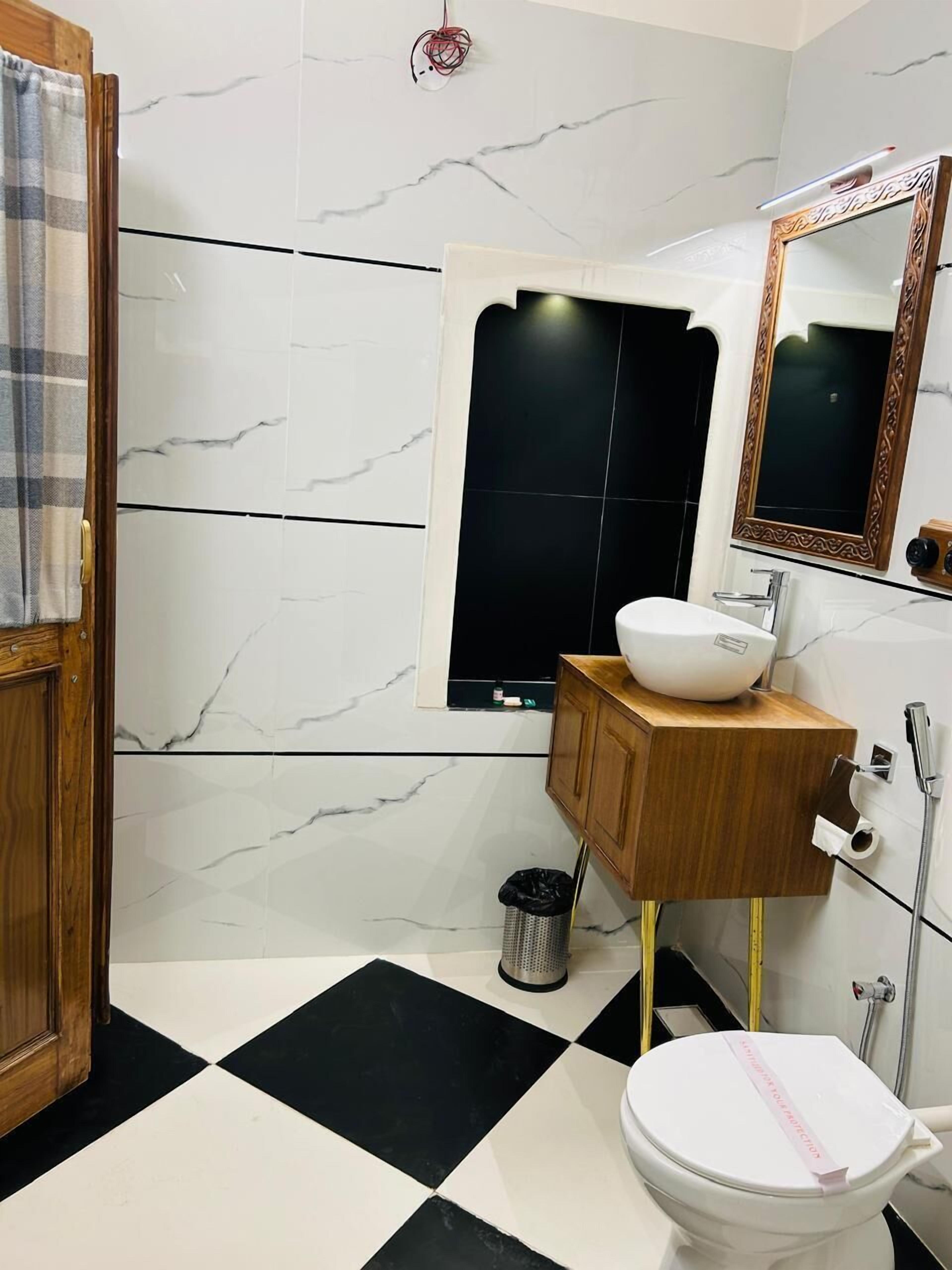 A bathroom with a black and white checkered floor, a wooden vanity, a white sink, and a toilet with a pink label.