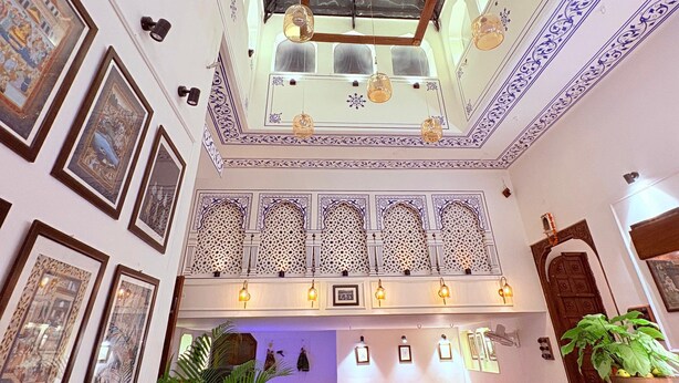 A spacious atrium with a high ceiling, decorative ceiling patterns, and a central seating area with a sofa and coffee table. - House Of Amer (Amer)