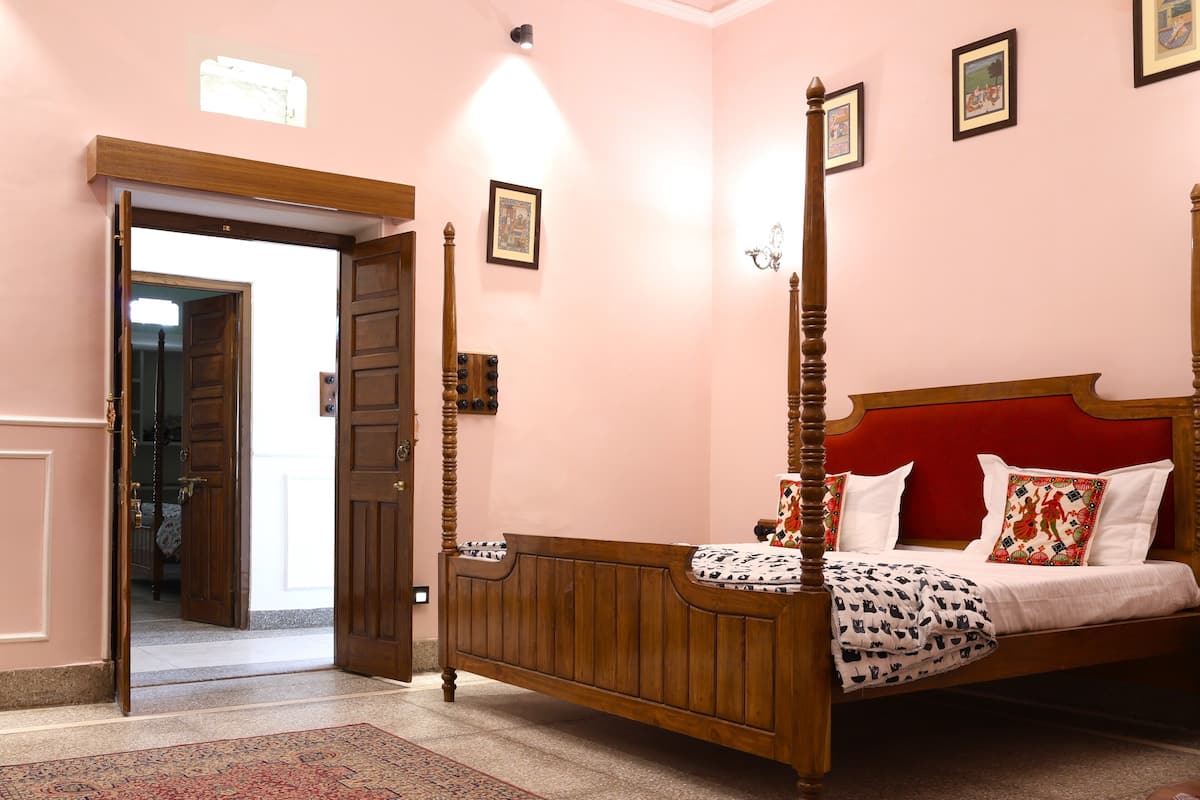 Un dormitorio con cama de madera con dosel, cabecero rojo y alfombra estampada.