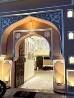 Un arco ornamentado que da acceso a una habitación con paredes de diseño y suelo de baldosas.