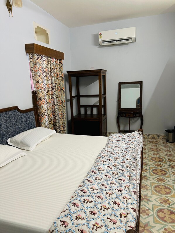 A bedroom with a bed, a wardrobe, an air conditioning unit, and a mirror.