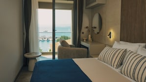A hotel room with a bed, a desk, a chair, a view of the sea, and a balcony. - ASYA RESİDENCE (Sinop)