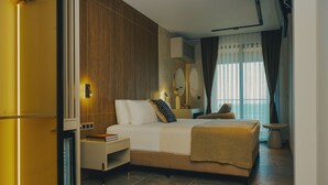 A modern hotel room with a bed, bedside table, and a small seating area. - ASYA RESİDENCE (Sinop)