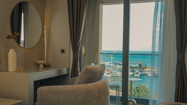 A modern hotel room with a large window offering a view of the marina and boats. - ASYA RESİDENCE (Sinop)