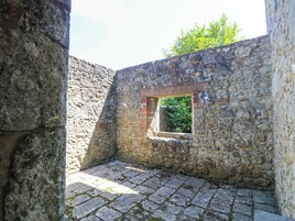 A stone-walled room with a small window and a stone floor.