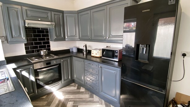 A modern kitchen with grey cabinets, a black refrigerator, a microwave, and a stove. - Modern room for short stay in Salford
ONLY SPARE ROOM TO LET IN Shared House (Salford)