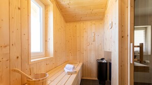 A wooden sauna room with a bench, a wooden bucket, and a towel. - Holiday Apartment in St. Englmar (Sankt Englmar)