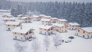 A cluster of wooden cabins with snow-covered roofs, surrounded by a forest. - Holiday Apartment in St. Englmar (Sankt Englmar)