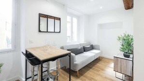 Ein moderner, minimalistischer Wohnraum mit Essbereich, Sofa und einem kleinen Beistelltisch mit Pflanze.
