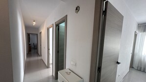 A hallway with a white cabinet, doors, and a ceiling light.