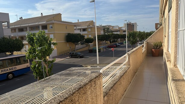A residential area with a balcony, a parked bus, and a road with cars.