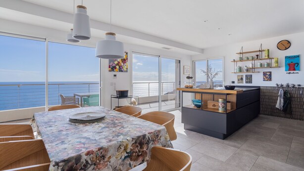 A modern kitchen with a central island, large windows, and a view of the sea. - Dream Vacation in a Beautiful Villa with Exceptional Sea View (Cerbère)