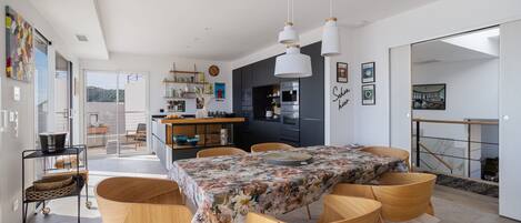 A modern kitchen with dark cabinets, a dining area with a floral tablecloth, and a view of the outdoors.