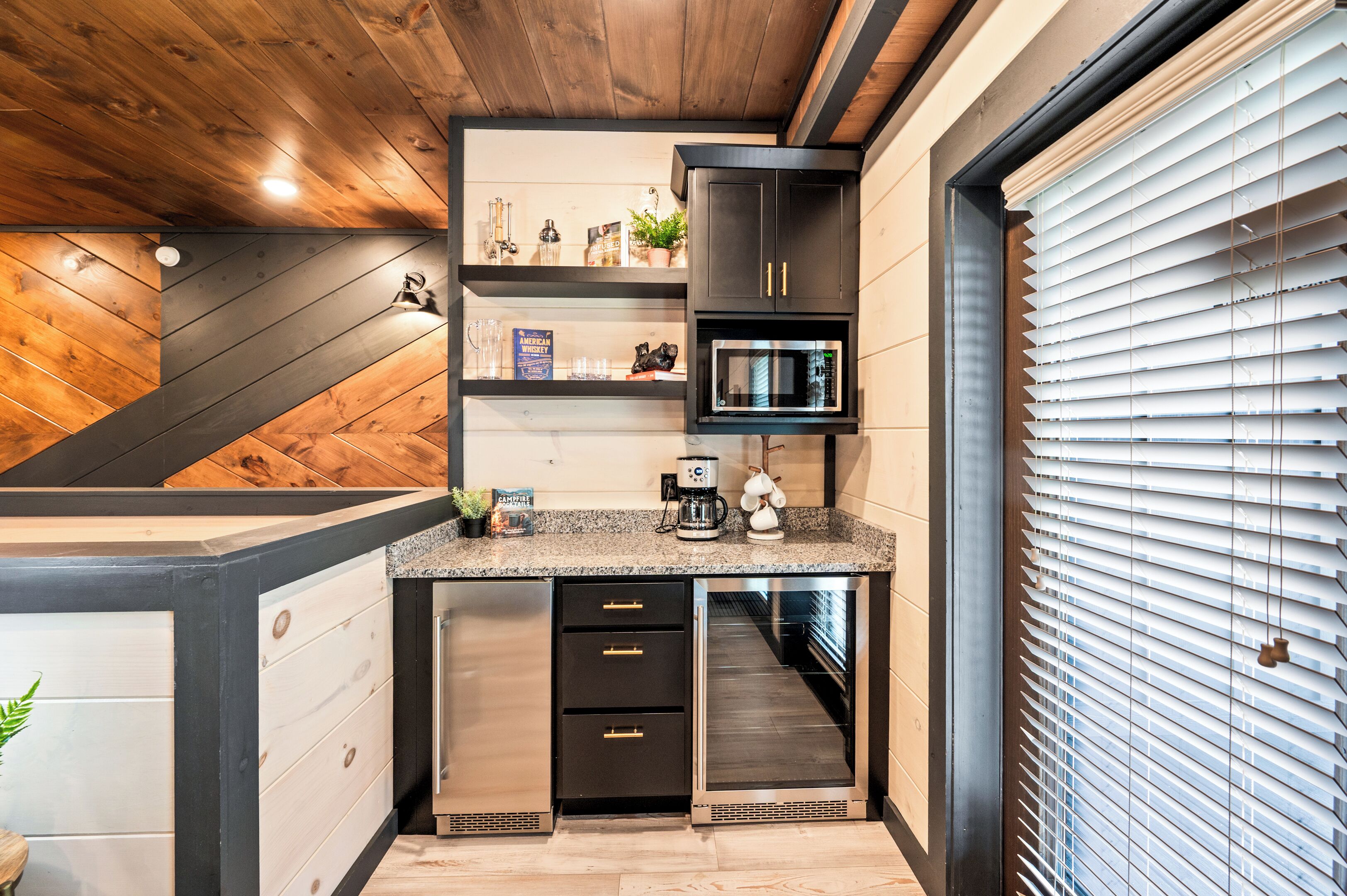 A compact kitchen with dark cabinetry, a built-in microwave, and a stainless steel refrigerator.