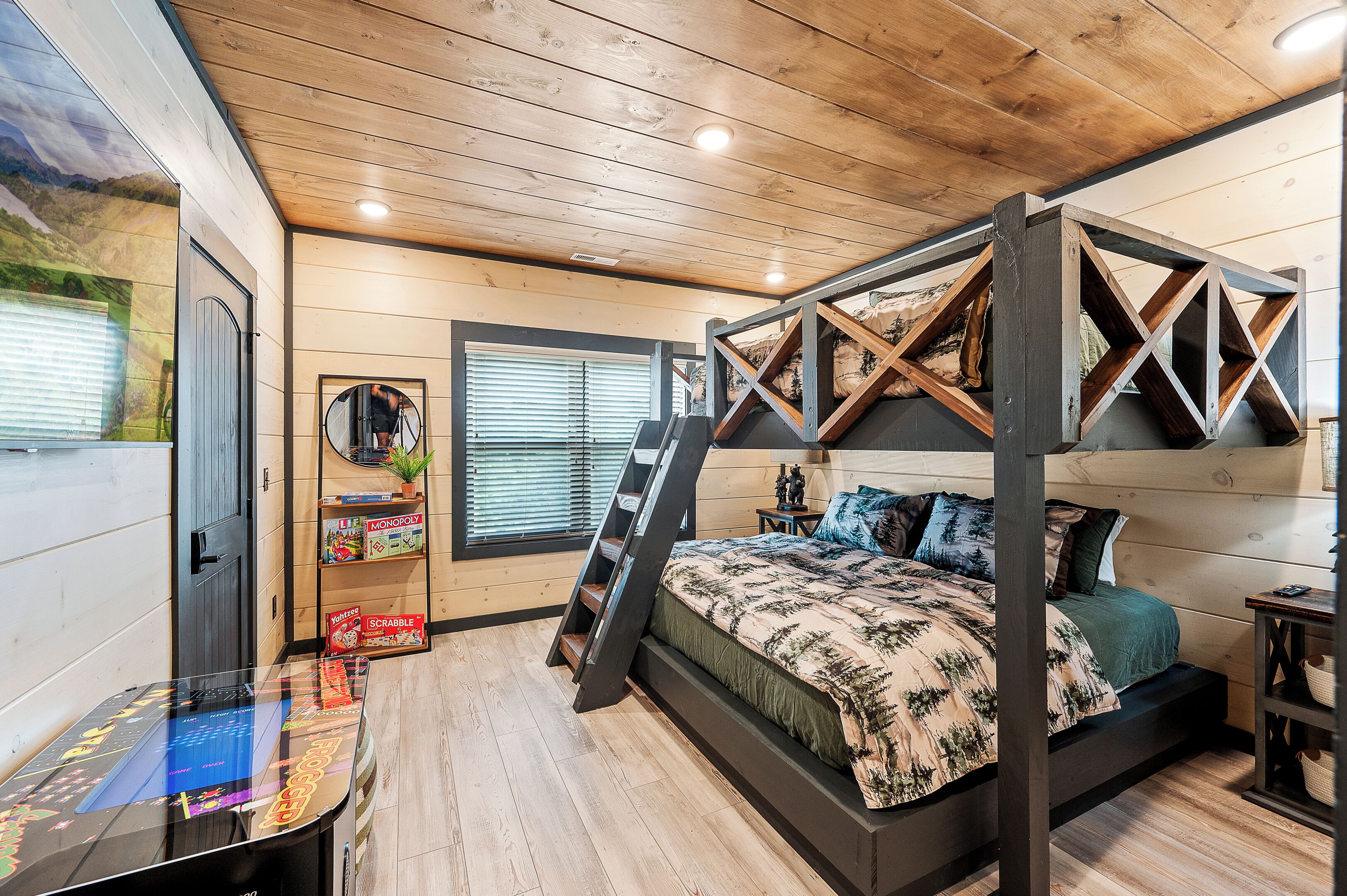 A bedroom with a four-poster bed, wooden flooring, a ladder, a desk with a computer, and a window with blinds.