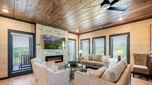 Una sala de estar acogedora con chimenea, asientos cómodos y ventanas amplias con persianas.