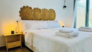 A neatly made bed with white linens, a bedside lamp, and a decorative woven headboard. - AQUAHOME- Beautiful apartment with pool at 3 minutes walking distance from Vera Playa (Palomares)