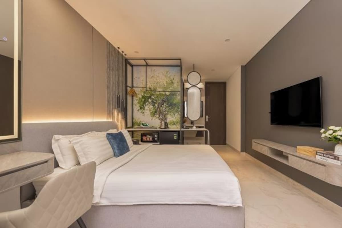 Een moderne hotelkamer met een groot bed, een bureau, een televisie en uitzicht op een boom door een raam.