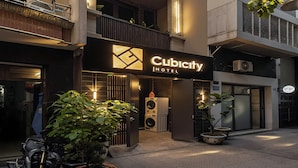 A hotel named Cubicity with a modern facade, multiple balconies, and potted plants.