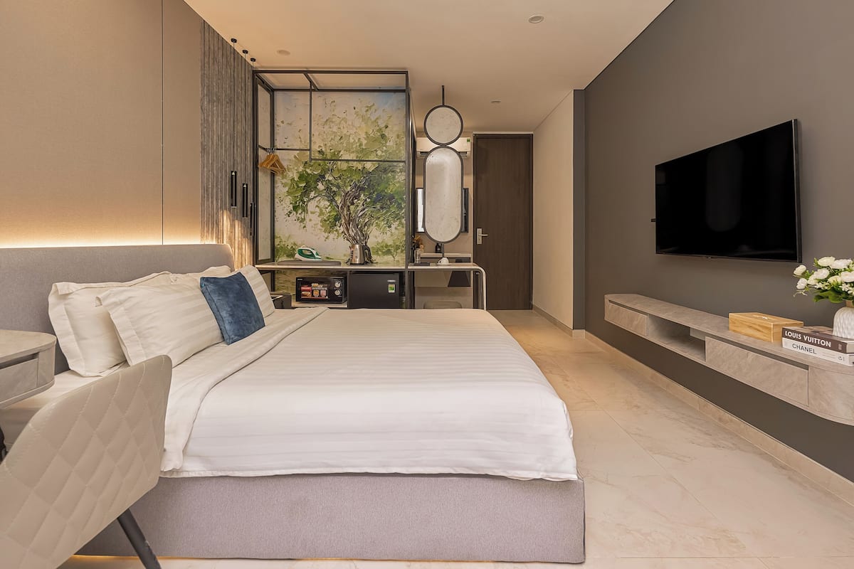 Een moderne slaapkamer met een groot bed, een bureau, een televisie en een wandplank met boeken.