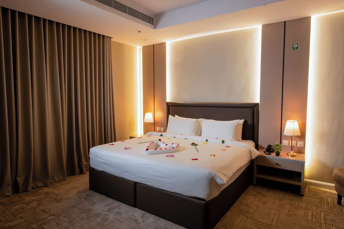 A hotel room with a large bed, a bedside table with a lamp, and a chair.