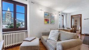 Una sala de estar con sofá, reposapiés y un comedor con mesa y sillas.
