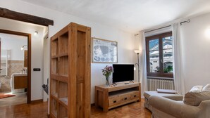 Una sala de estar con un mueble bajo de madera para el televisor, un sofá, un ventanal con vistas y un cuadro colgado en la pared.