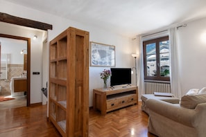 A living room with a wooden TV stand, a sofa, a large window with a view, and a wall-mounted picture.