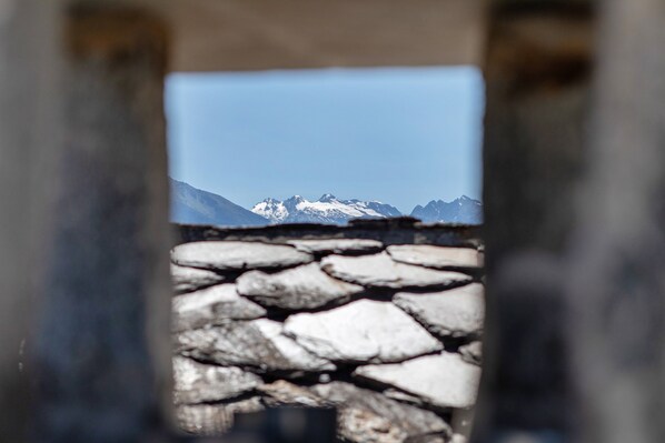 Un mur de pierre offrant une vue sur des montagnes enneigées.