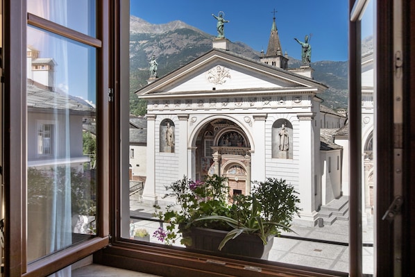 A view through a window of a building with classical architecture, including statues and a dome.