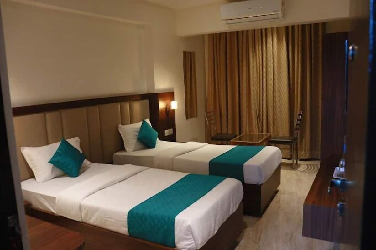 A hotel room with two beds, a desk, and a chair.