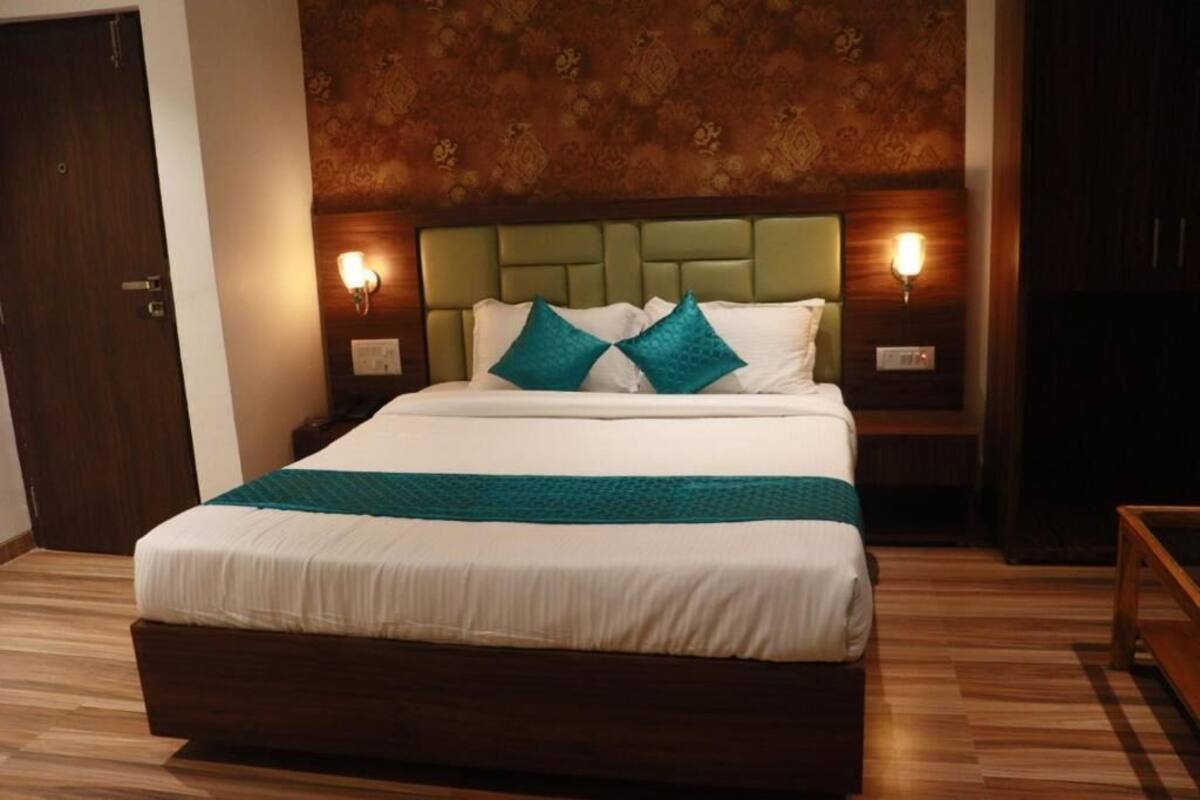 A hotel room with a large bed, two bedside tables, and a headboard with wall sconces.