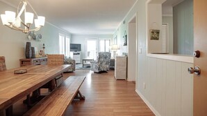 Een ruime woonkamer met een houten eettafel, een kroonluchter en uitzicht op de keuken.