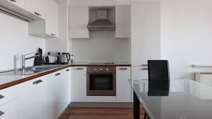 Una cucina moderna con mobili bianchi, forno integrato e cappa aspirante in acciaio inossidabile.