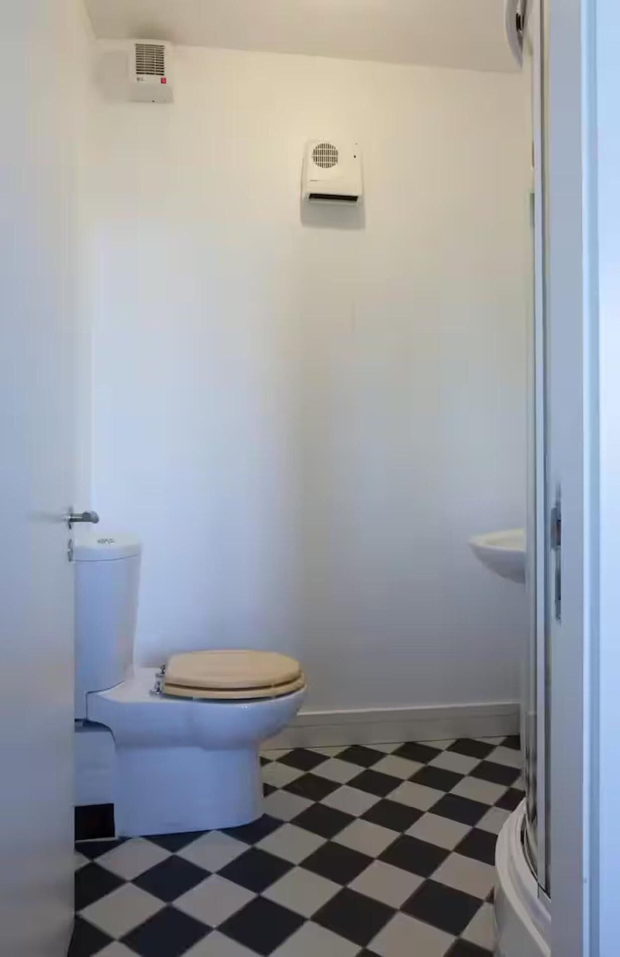 Un baño pequeño con inodoro, lavamanos y ducha.