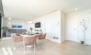 Un salon moderne comprenant un coin repas, un canapé gris, un téléviseur à écran plat et une grande fenêtre.