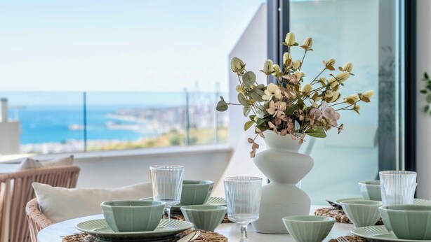 A dining table with green plates and glasses, a white vase with flowers, and wicker chairs. - The Palm Escape – Seaview, Pool & Terrace | Higueron West, Fuengirola (Fuengirola)