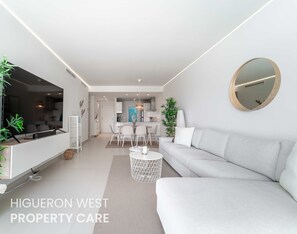 Ein modernes Wohnzimmer mit einer Couch, einem Essbereich und einer Küche im Hintergrund.