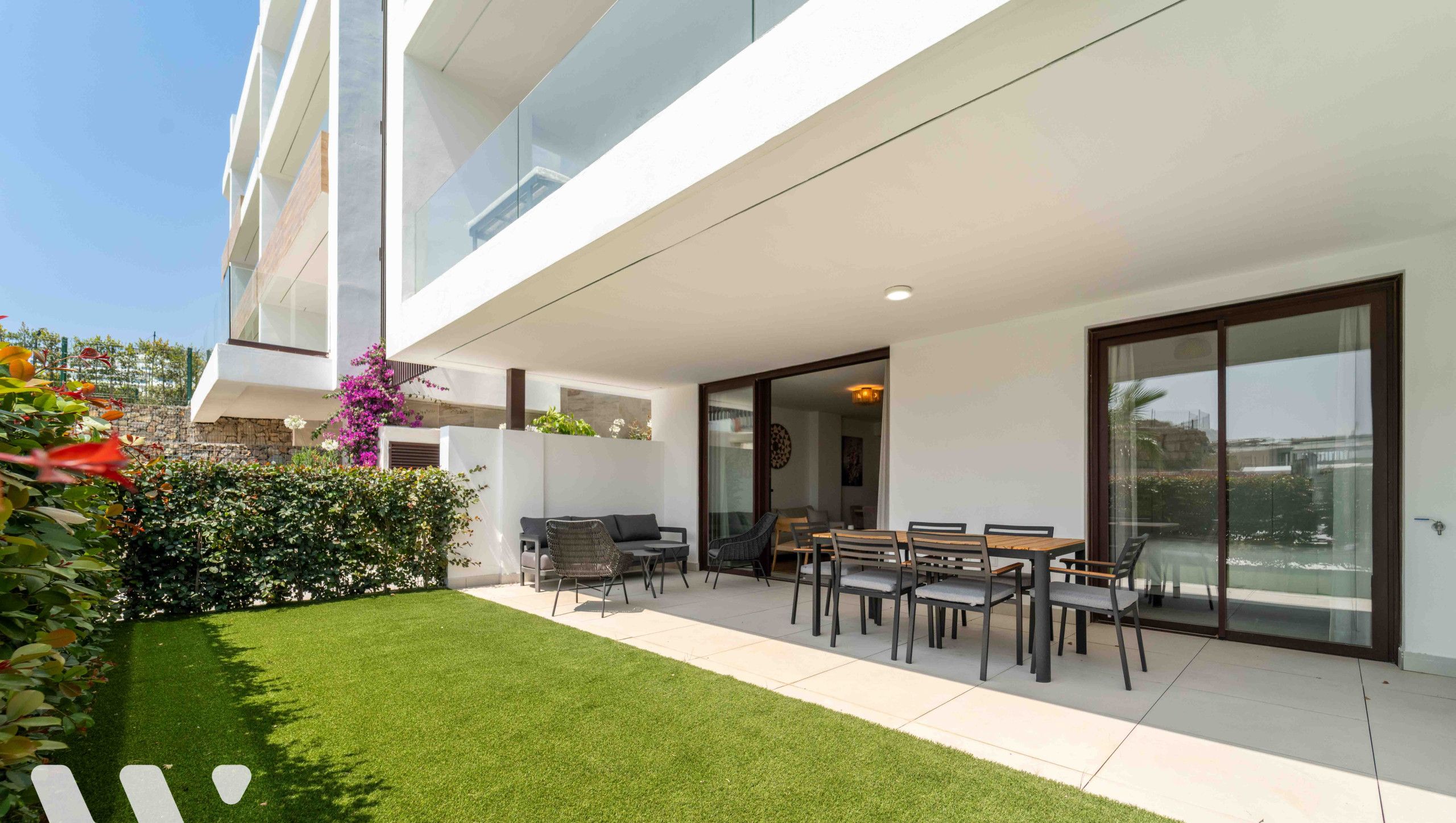 A modern building with a patio area featuring outdoor furniture and a well-maintained lawn.