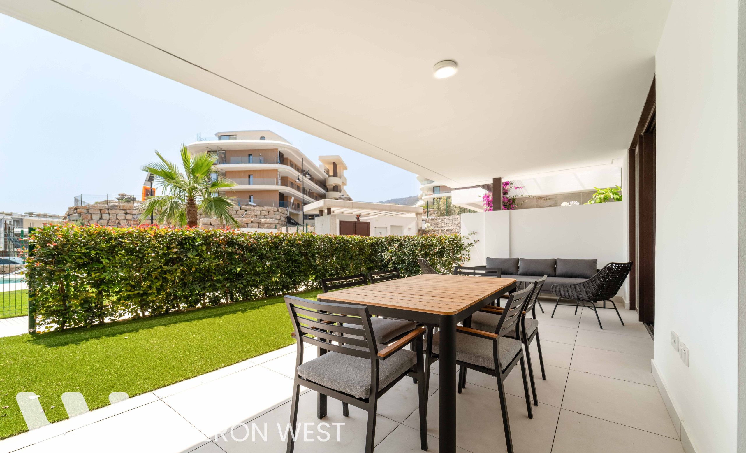 Un balcon avec une table et des chaises, une vue sur les bâtiments et une pelouse bien entretenue.