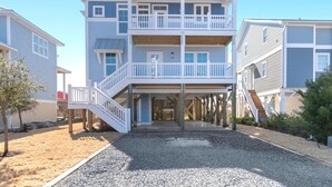 A multi-story beachfront property with a covered walkway and a staircase leading to the upper levels. - 5513 E Pelican Drive 5 bedrooms, private pool, and easy beach access. (Oak Island)