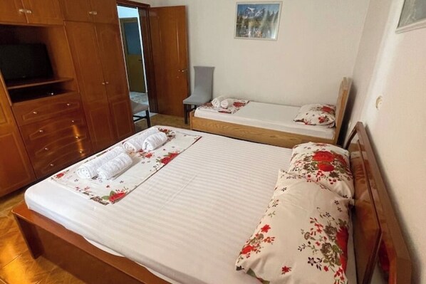 Une chambre avec deux lits, des meubles en bois, une chaise et un téléviseur.