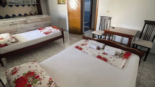 A hotel room with two single beds, a small table, a chair, and a bathroom visible through an open door. - Olympia’s Apartment – Spacious Retreat for Up to 6 Guests (Fishta)