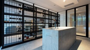 A modern bathroom with a concrete sink, a black metal partition, and a view of parked cars through the partition. - Signature 81 in Brighton (Brighton)