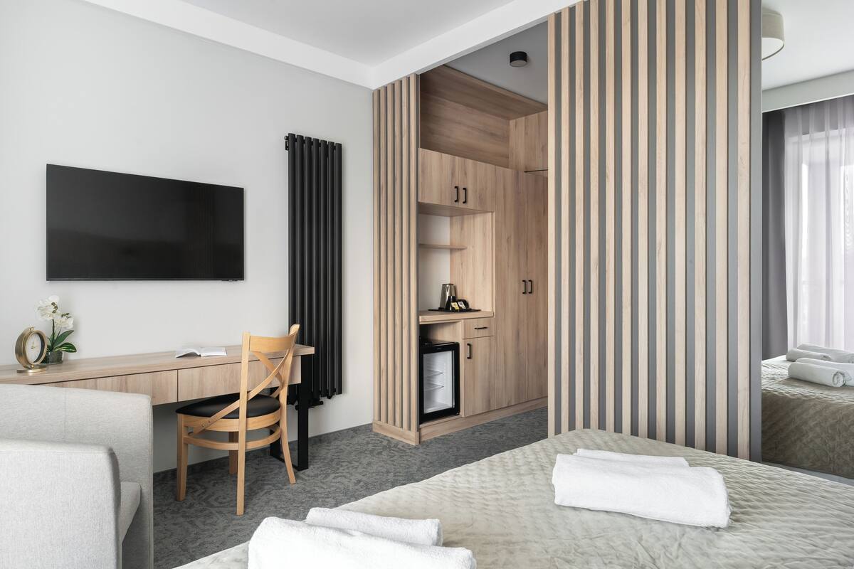 Une chambre d’hôtel équipée d’un lit, d’un bureau, d’une chaise, d’une télévision et d’un mini-bar.