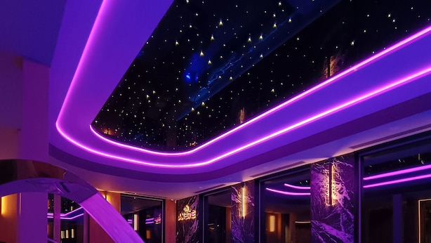 A modern indoor pool area with a starry ceiling and purple lighting. - Rezydencja Ambre (Łeba)