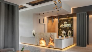 A modern reception desk with a marble top, a wooden accent wall, and a sign reading "AMBRE RESIDENCE". - Rezydencja Ambre (Łeba)