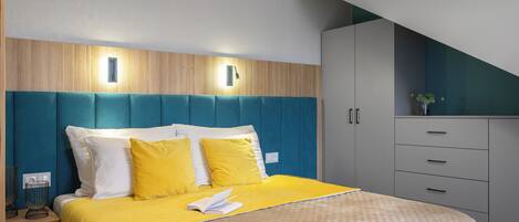 A modern hotel room with a bed, bedside tables, a nightstand, and a built-in wardrobe.