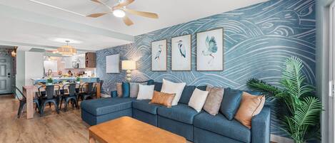 A modern living room with a sectional sofa, wooden coffee table, and a ceiling fan.